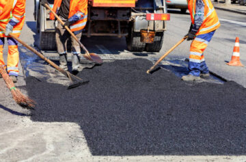 The road workers' working group updates part of the road with fresh hot asphalt and smoothes it for repair.
